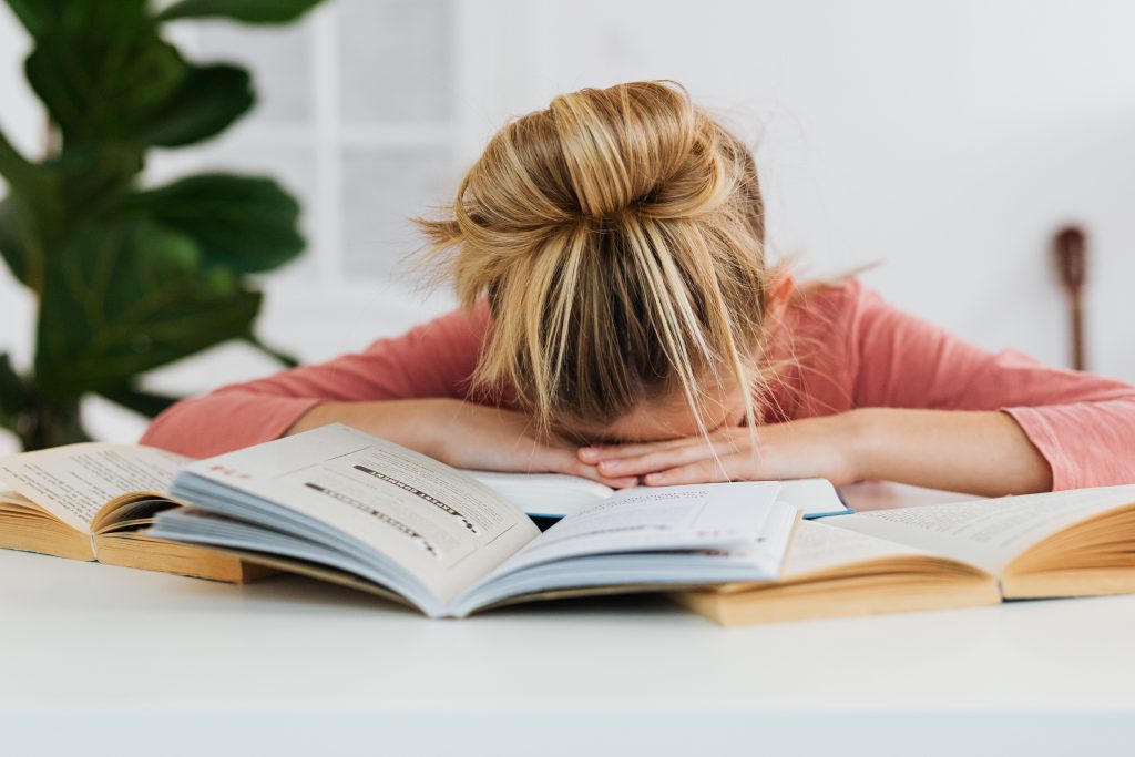 person reading book near window desk