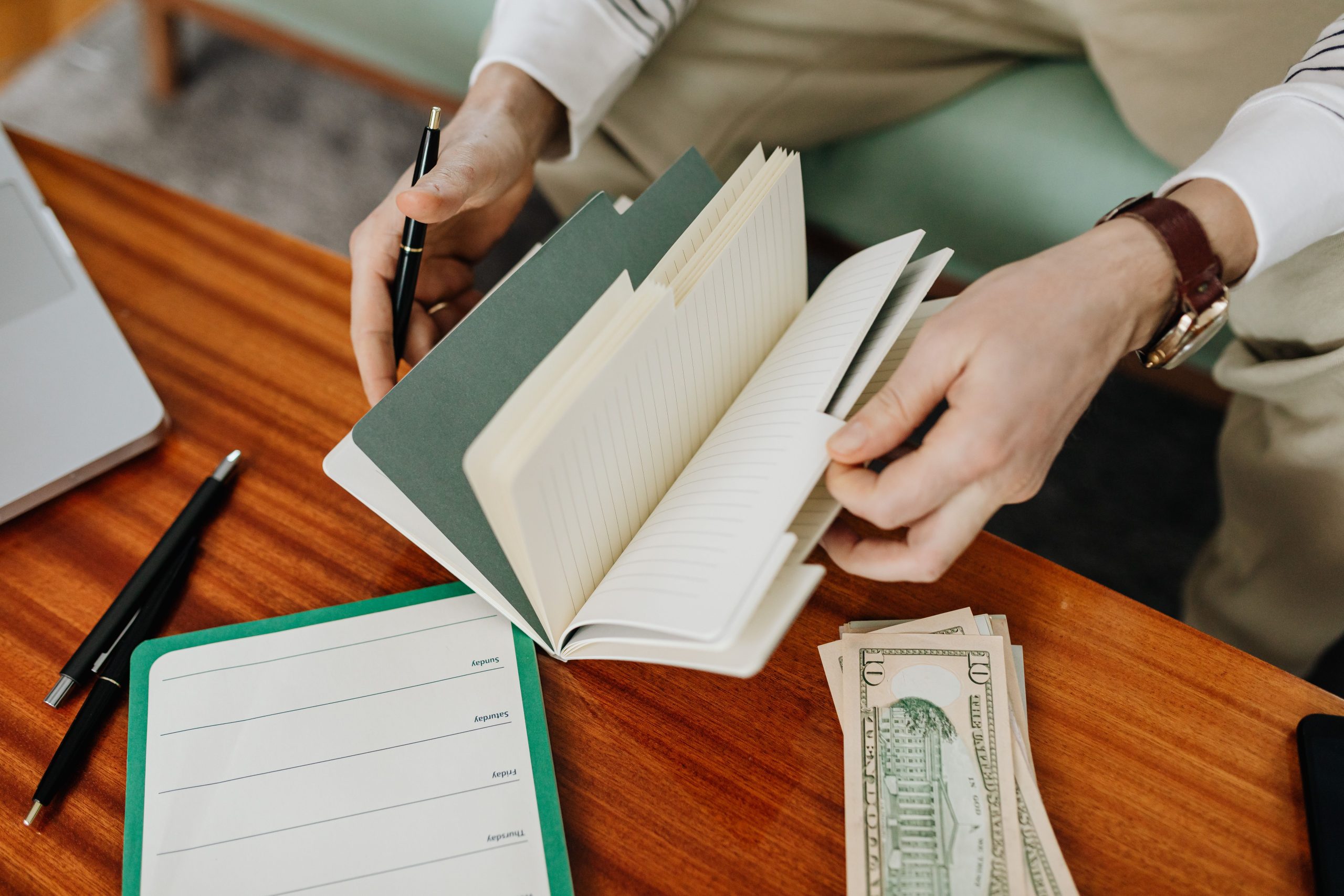 person holding notebook planning money